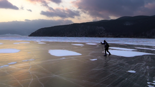 Man Are Skating on the Ice of Frozen Lake Baikal During Beautiful Sunset.