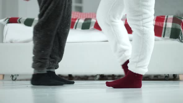 Feet of Joyful Couple Dancing in Pajamas and Socks alt