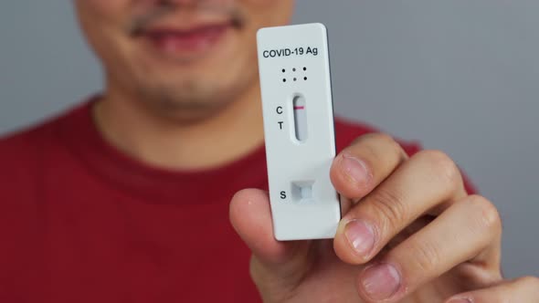happy man holding Coronavirus(Covid-19) negative test result with Antigen Rapid Test kit (ATK)