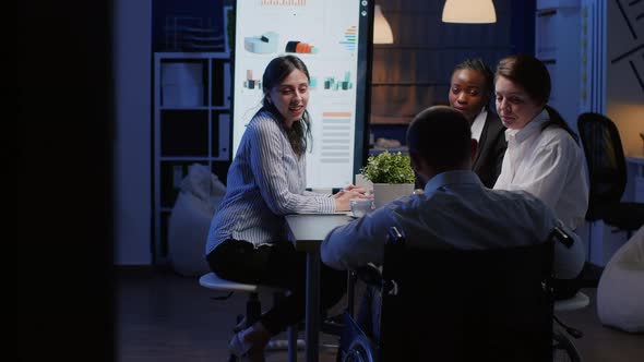 Focused Disabled Businessman in Wheelchair Sharing Financial Paperwork alt