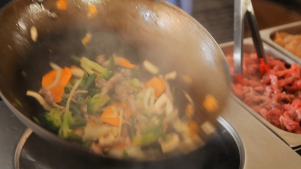 Professional Cook Frying Vegetables and Meat at the Street Food Festival.