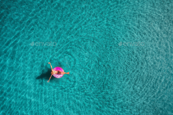 Aerial view of young woman swimming on the pink swim ring - Stock Photo - Images