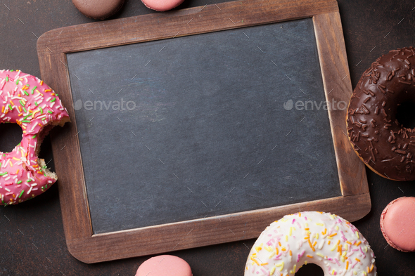 Chalkboard and colorful donuts on stone table