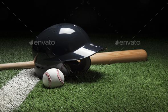 Baseball Helmet Ball and Bat on Green Field with Dark Background - Stock Photo - Images