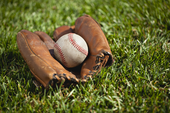 Old Baseball Mitt and Ball on Grass Field