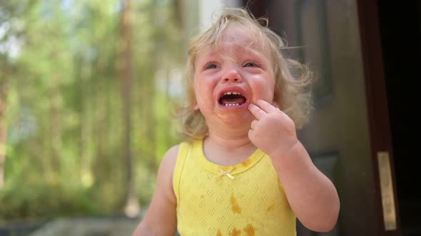 Close Up Portrait of Little Funny Cute Blonde Girl Child Toddler in Yellow Dirty Bodysuit Crying