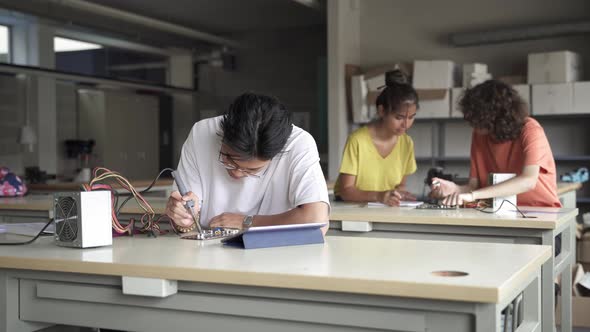 Asian Student Soldering Electronics Circuit Board in the Science Technology Workshop Digital alt