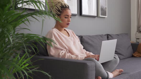 Female Using Laptop While Sitting on Comfortable Sofa at Home