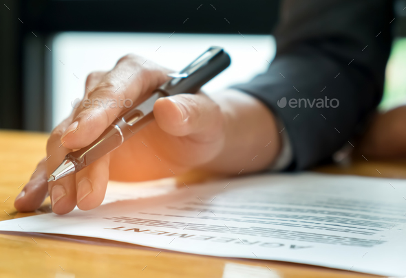 Businessmen holding pens in hand reading documents on the desk,B