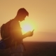 Always and Everywhere in Touch. A Traveler with a Backpack Uses a Smartphone. Silhouette on Sunset - VideoHive Item for Sale