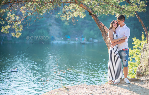 Romantic young couple standing on cliff over river