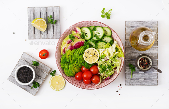 Vegan salad of fresh vegetables - tomatoes, cucumber, watermelon radish and avocado on bowl.
