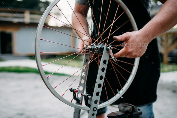 Male person adjusts bike spokes and wheel - Stock Photo - Images
