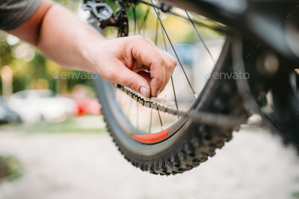 Bicycle mechanic in apron adjusts bike chain - Stock Photo - Images