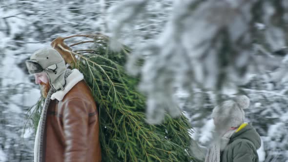 Father and Son Carrying Christmas Tree Home alt