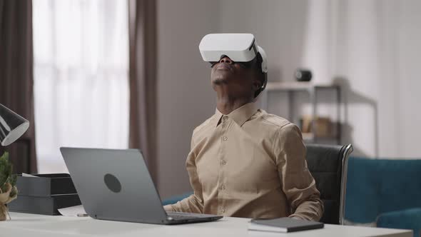 Using Virtual Reality for Education Young Black Guy is Wearing Headmounted Display Sitting at Table alt