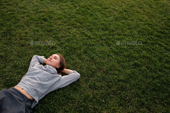 Beautiful young european woman lays down on grass and rests
