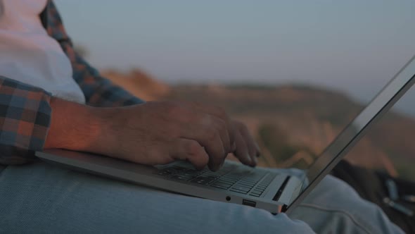 A man's hands typing on laptop alt
