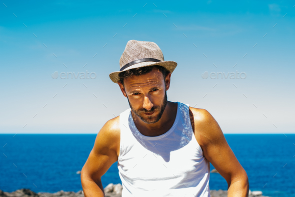 Muscular man in hat on coast