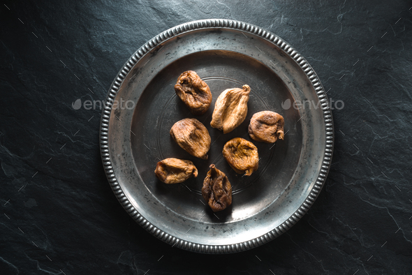 Dry figs on a tin plate on a gray stone