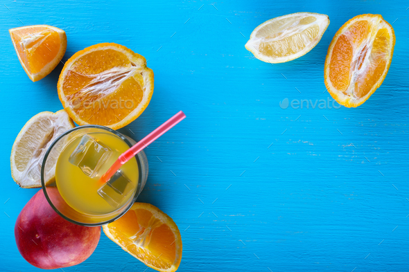 Fresh raw fruits and glass of juice on blue background - Stock Photo - Images