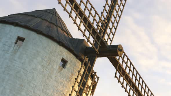 Closeup shot of a vintage Spanish windmill's wings rotating slowly at sunset. 4K