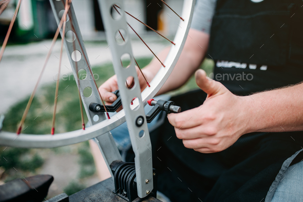 Male person adjusts bike spokes and wheel - Stock Photo - Images