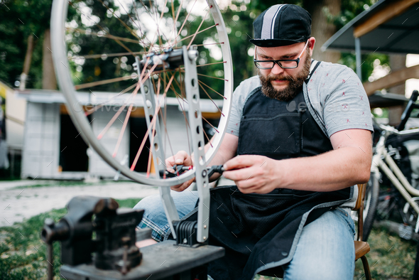 Male person adjusts bike spokes and wheel - Stock Photo - Images