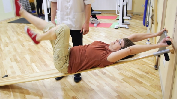 Physiotherapist Helping Elderly Woman Rotate Legs, Doing Exercises in Fitness Room