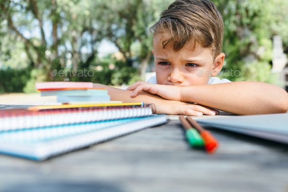 Little schoolboy with notepads at table - Stock Photo - Images