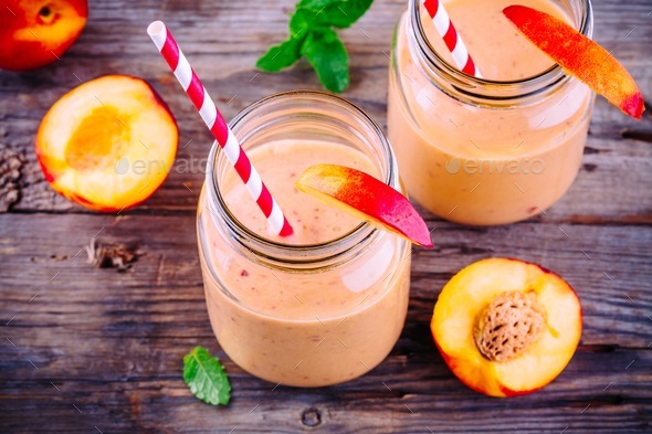 Nectarine smoothies in a mason jar with mint on wooden background