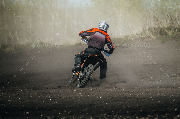 Racer motorcycle rides on dusty track