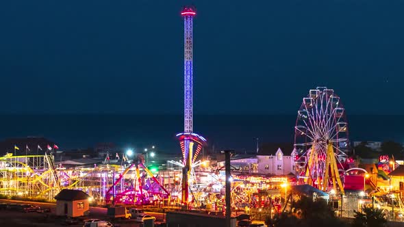 Lights of the Ferris Wheel and Other Attractions at Night Against the Backdrop of the Sea Coast.