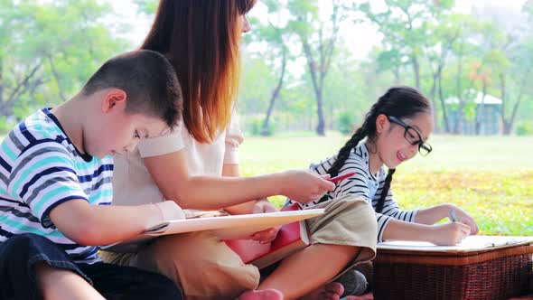 Happy Asian family on vacation picnic in the park. drawing a picture activity