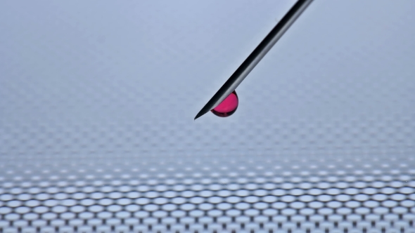 With a Needle From the Syringe Flows a Drop of Red Liquid alt