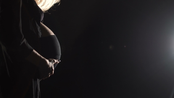 беременная женщина отдыхает в темной комнате с повязкой на глазах