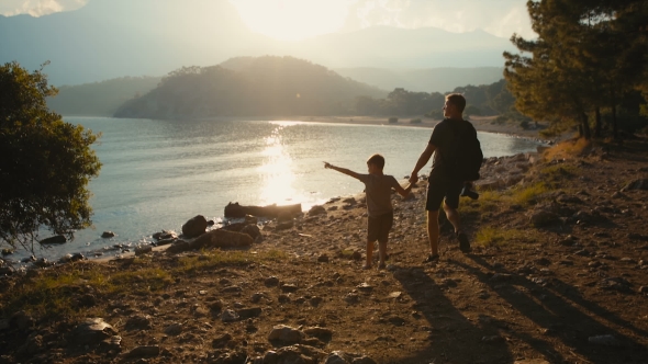 Father and Son Walk Along the Coast Holding Hands