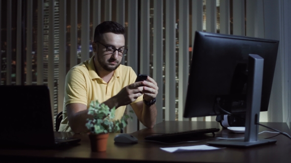 Man Using Phone in Office at Night alt