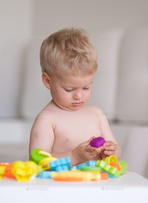 Boy playing with colorful modeling clay (plasticine or dough)