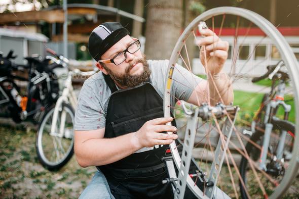 Mechanic adjusts bike spokes and repair wheel - Stock Photo - Images