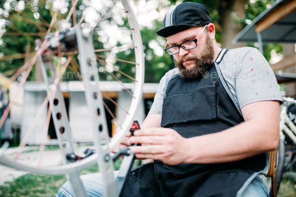 Mechanic adjusts bike spokes and repair wheel - Stock Photo - Images