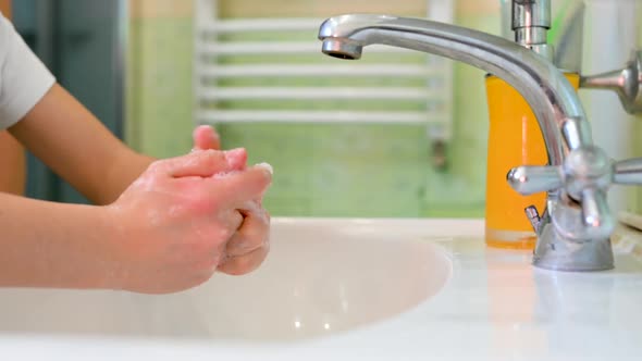 child washes his hands with soap with a bath.