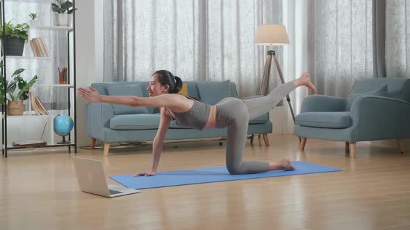Athletic Female Doing Yoga In Balancing Table Pose On The Mat At Home With Online Coach Via Laptop alt