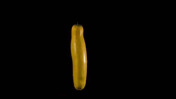 Yellow zucchini on black background seems to dance. Room for text. Part of series. alt