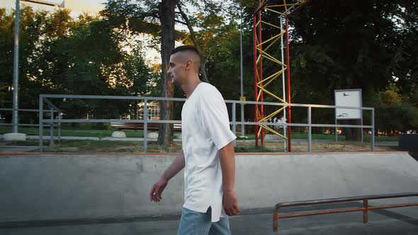 Young Fellow is Walking Along Pump Track of Rollerdrome and Performing Back Flip alt