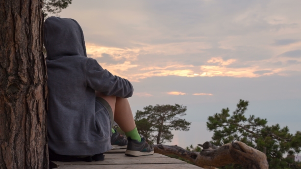 Girl in a Hoodie Sits, and Contemplates the Sky alt
