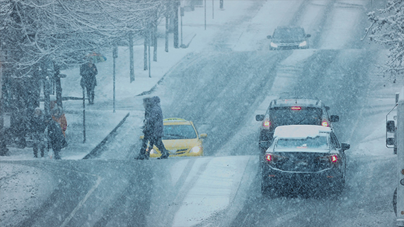 People Crossing Busy Road In Snowstorm alt