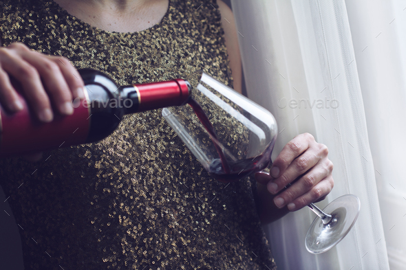 woman with gold spangle dress pouring red wine into a glass - Stock Photo - Images