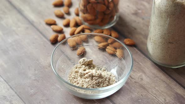 Women Hand with Spoon Pouring Almond Powder in Bowl alt