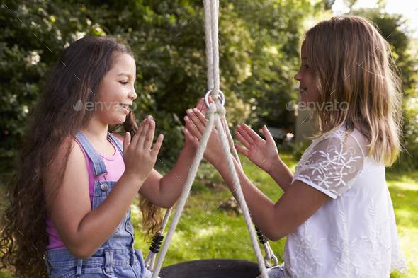 Two Girls Sitting On Swing Playing Clapping Game